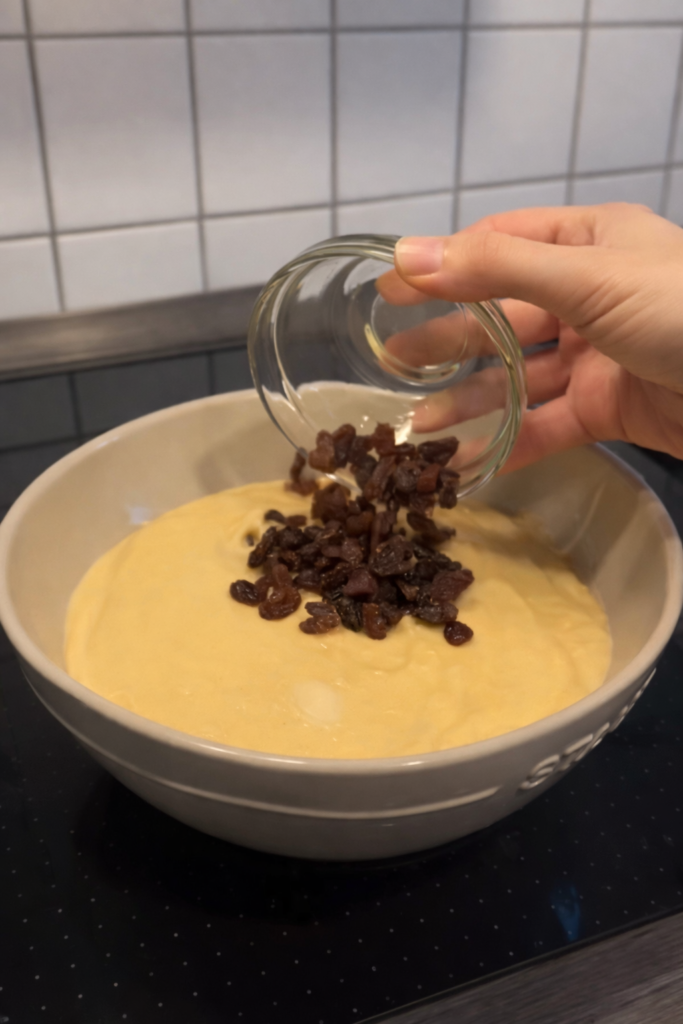 Dodavanje grožđica u smjesu za domaći kolač prije pečenja.