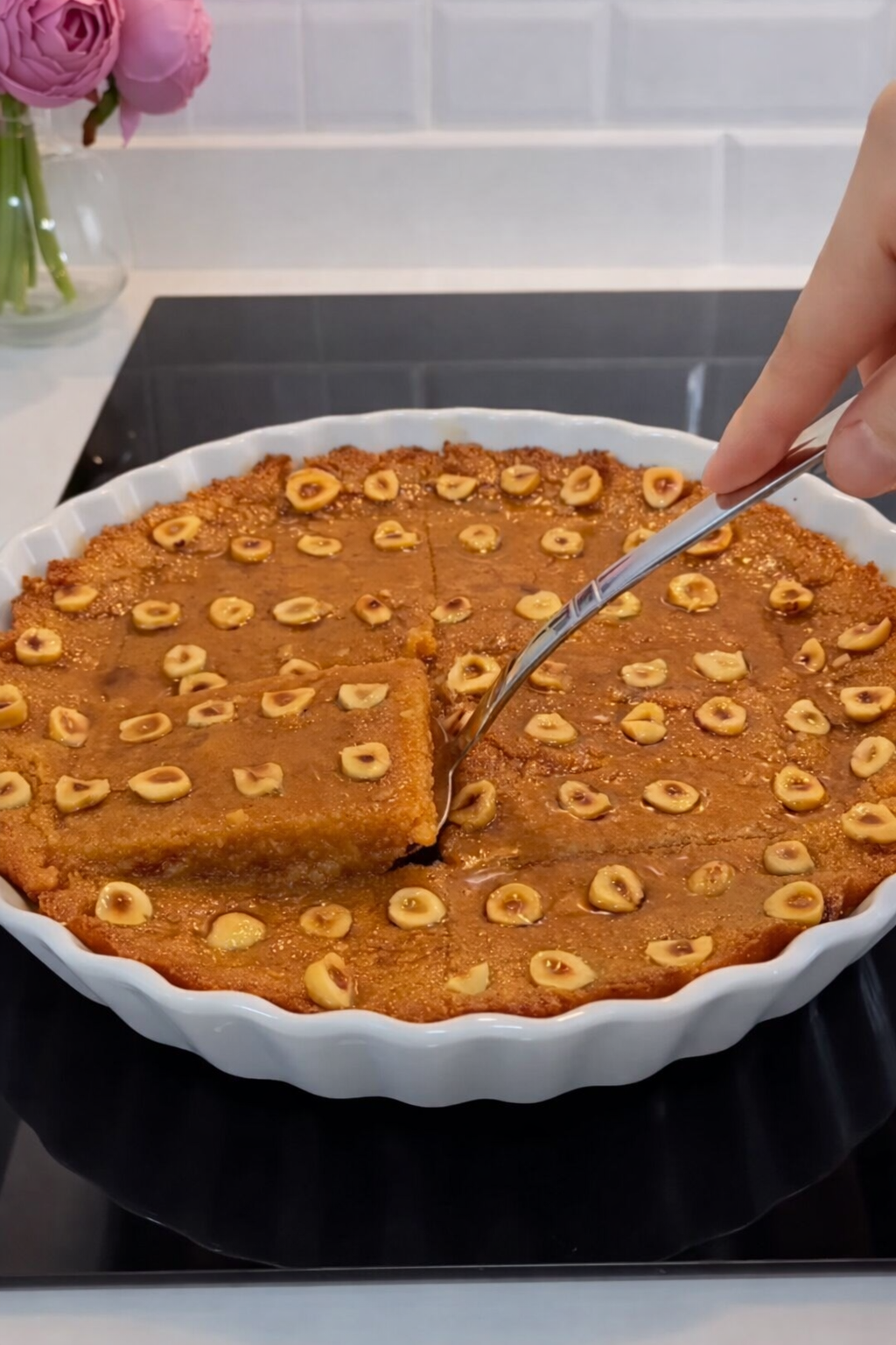 Karamelni desert sa grizom i bademima, izrezan komad u plehu prije serviranja.