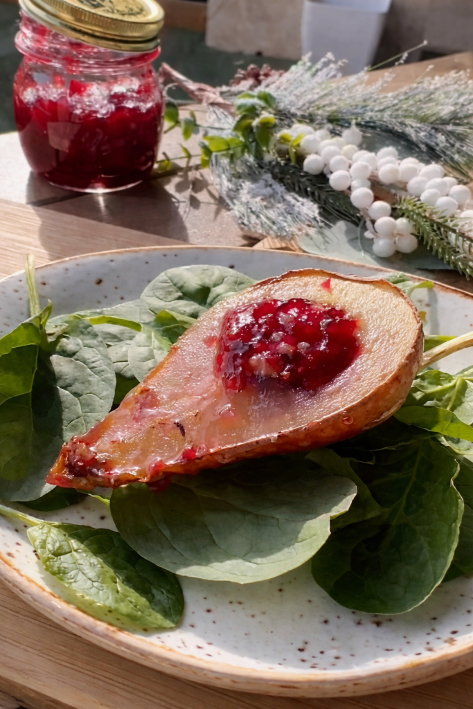 Pečena kruška punjena džemom od malina, servirana na svježim listovima