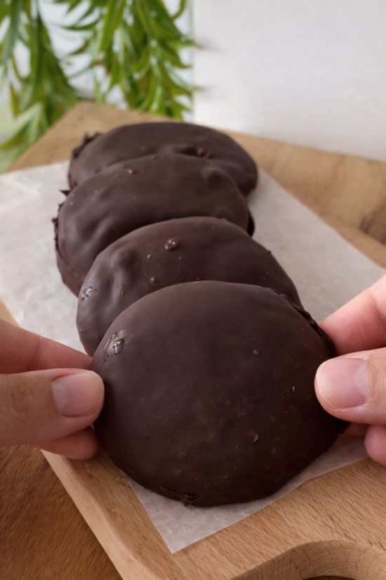 Domaći smrznuti jogurt keksi obloženi tamnom čokoladom posluženi na drvenoj dasci, brz i zdrav desert bez pečenja.