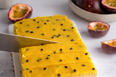 Cheesecake sa marakujom preliven gustim žutim prelivom i sjemenkama marakuje, svježe rezan na kriške