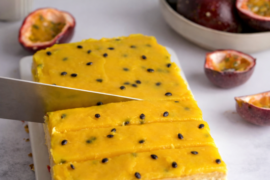 Cheesecake sa marakujom preliven gustim žutim prelivom i sjemenkama marakuje, svježe rezan na kriške