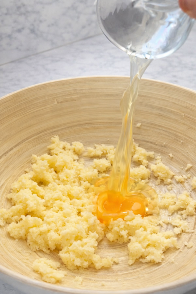 Dodavanje jajeta u smjesu od maslaca i šećera za pripremu muffina s borovnicama