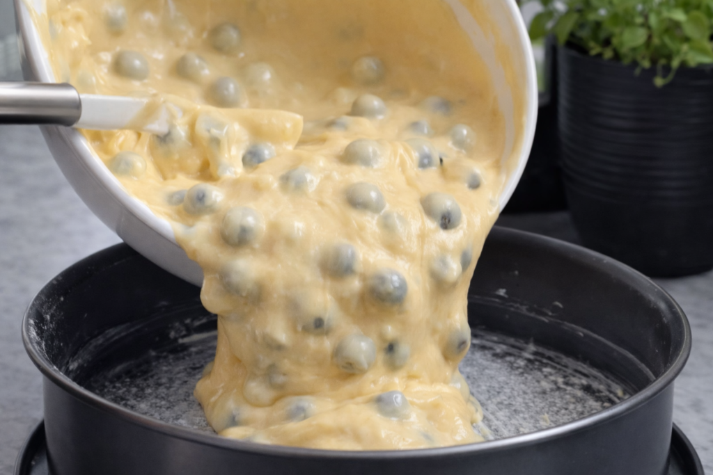 Ulijevanje smjese za kolač s borovnicama u kalup promjera 26 cm prije pečenja.