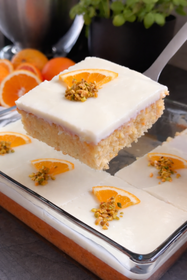 Kolač od narandže sa puding kremom u staklenoj tepsiji, sočan domaći kolač preliven kremom i dekorisan kriškama narandže