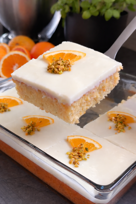 Kolač od narandže sa puding kremom u staklenoj tepsiji, sočan domaći kolač preliven kremom i dekorisan kriškama narandže