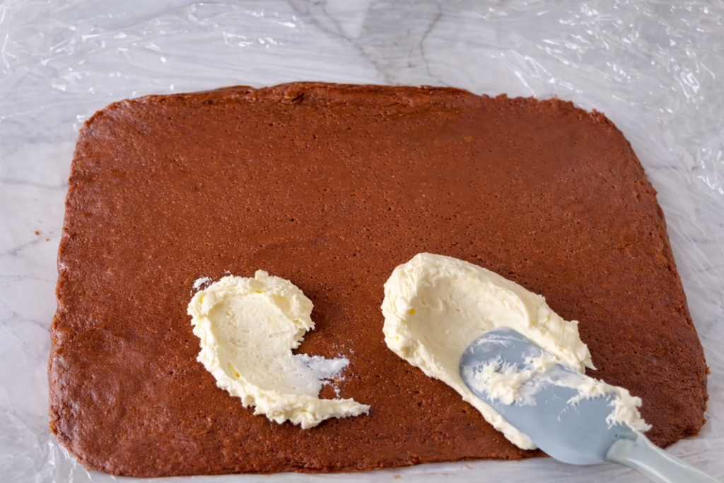 Mazanje mascarpone kreme preko Biscoff podloge prije rolanja rolata bez pečenja