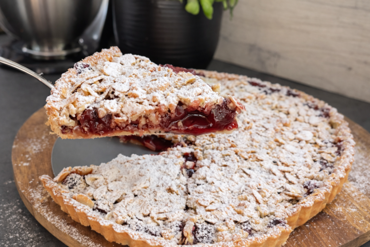 Pita s višnjama sa prhkim tijestom i sočnim nadjevom, posuta šećerom u prahu, presjek domaće cherry pie