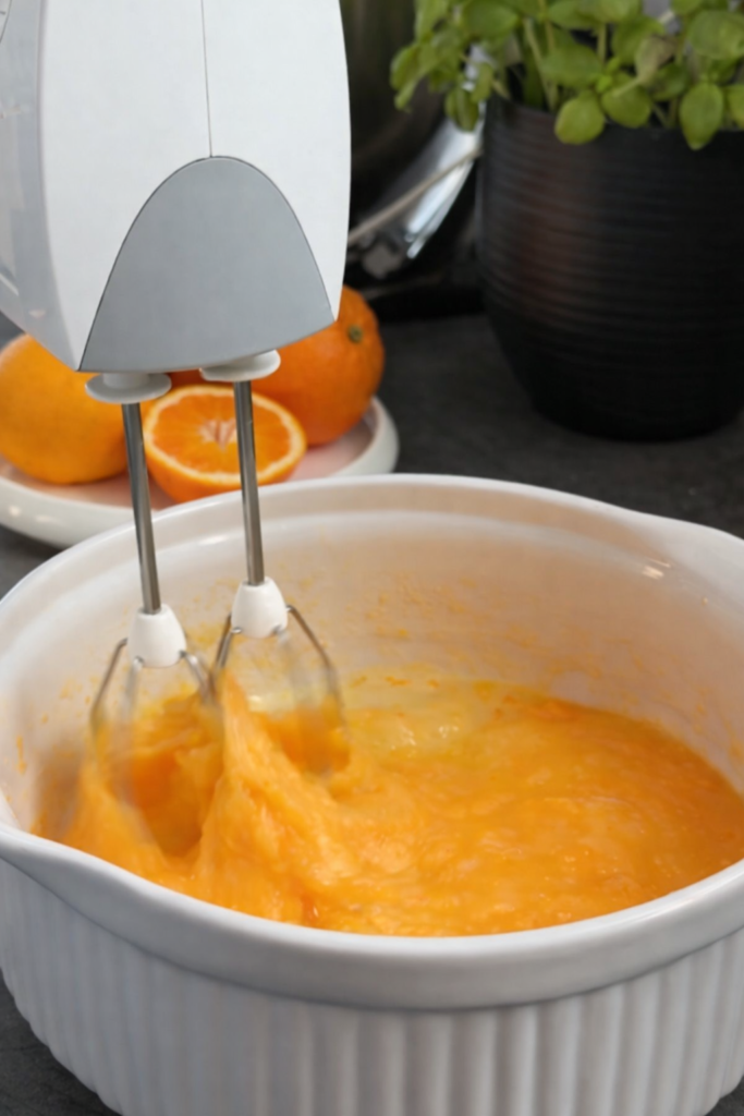 Priprema kolača od narandže – mućenje smjese sa jajima, sokom i koricom narandže prije pečenja