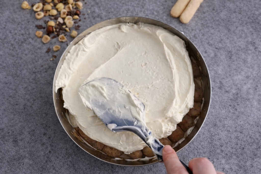 Mascarpone krema se ravnomjerno razmazuje preko sloja piškota u kalupu