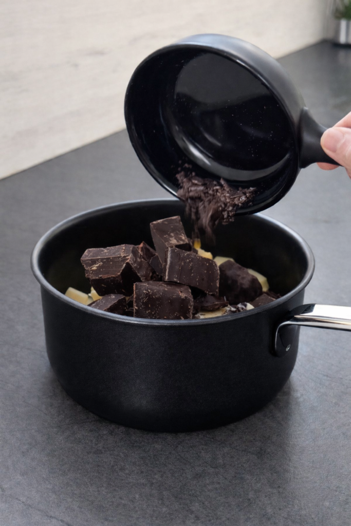 Topljenje tamne čokolade i maslaca u šerpi za pripremu ganache preliva za čokoladni kolač