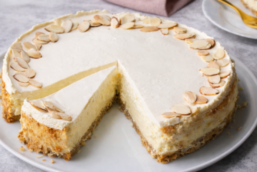 Čizkejk od badema sa tajnom savršene teksture i tostiranim bademima na vrhu, prikazan presjek