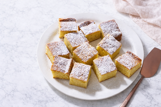 Najmekši kolač od putera posut šećerom u prahu i narezan na kocke