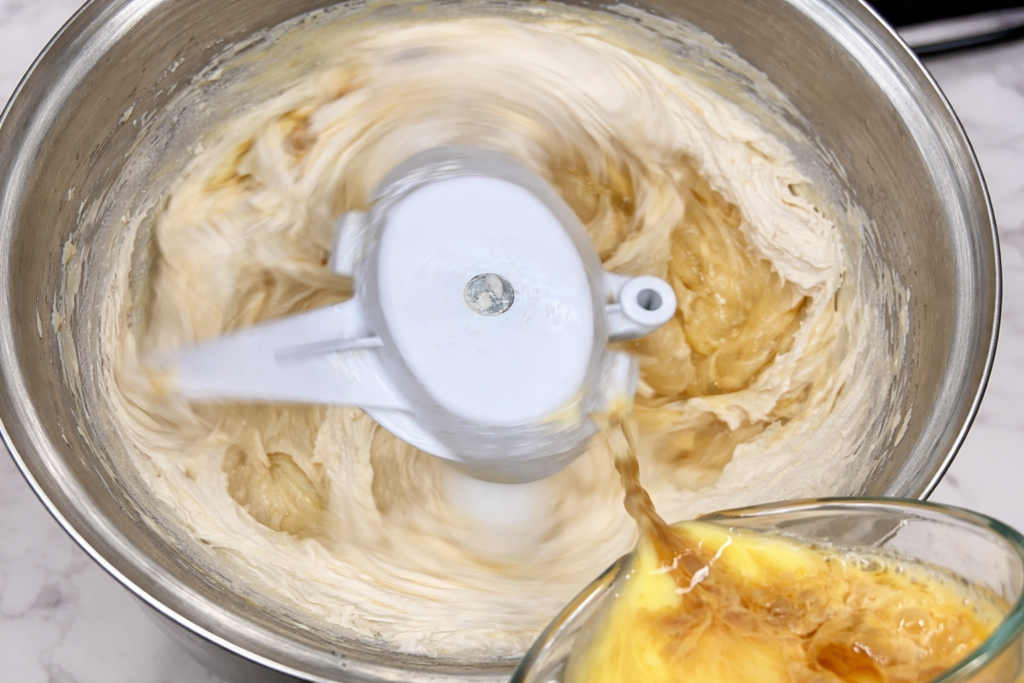 Dodavanje smjese jaja i mlijeka u tijesto za kolač od vanilije u samostojećem mikseru