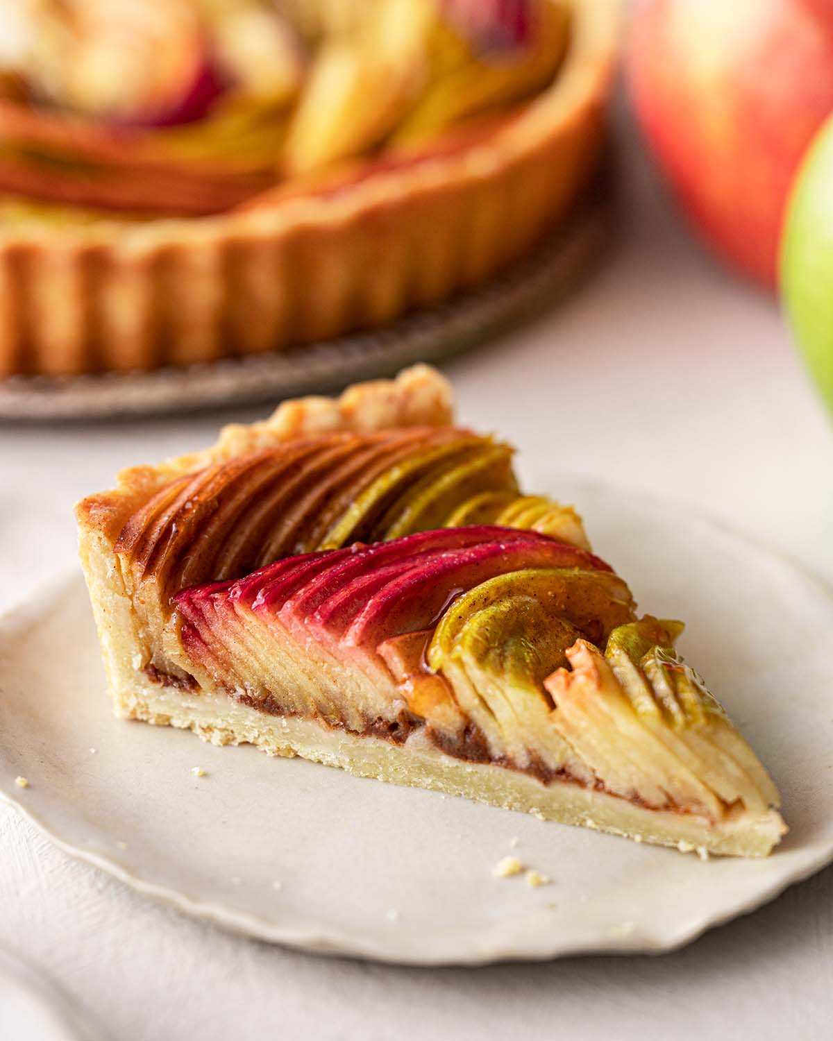Domaći tart sa jabukama složenim u krug na prhkom tijestu, pečen do zlatne boje.