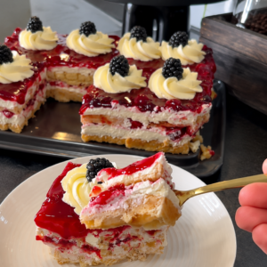 Kremasta torta od vafela sa mascarpone kremom i preljevom od šumskog voća, ukrašena kupinama i ružicama od šlaga.