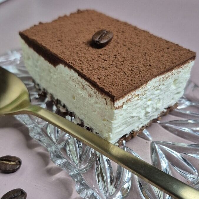 Tiramisu s Nutellom bez pečenja narezan na kocke i posut kakao prahom.