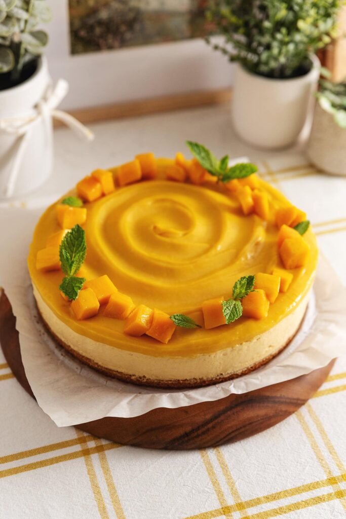 Cijela torta od mango moussea ukrašena svježim mangom i listićima mente.