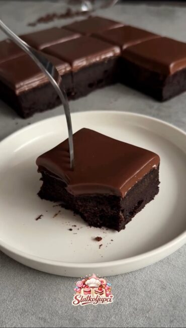 Komad čokoladnog kolača s ganache preljevom na bijelom tanjiru