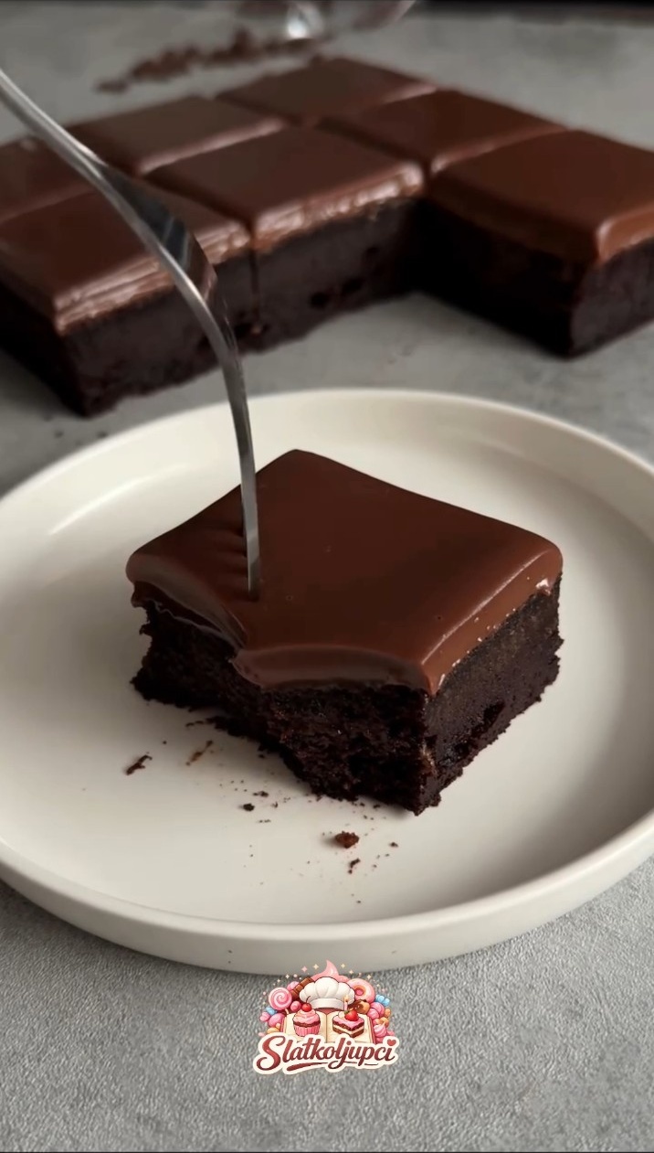 Komad čokoladnog kolača s ganache preljevom na bijelom tanjiru