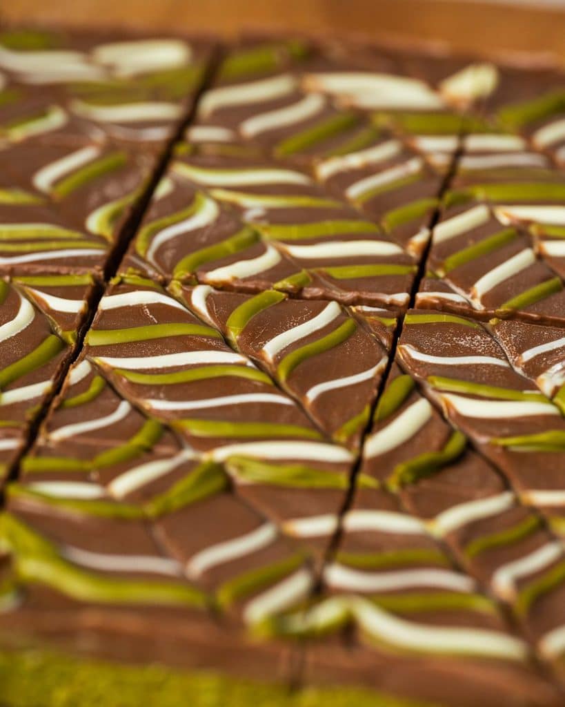 Krupni kadar izrezanih Dubai brownieja s čokoladnim vrhom i zelenim i bijelim šarama