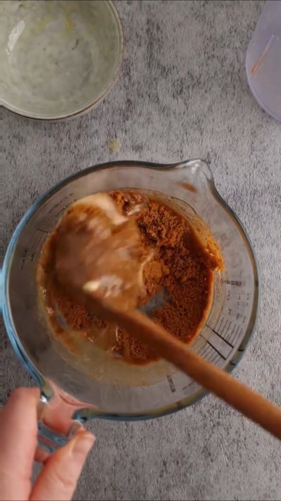 Miješanje mljevenog keksa i maslaca špatulom u staklenoj posudi za podlogu čokoladnog tarta